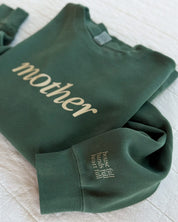 Adult pigment crewneck in alpine with 'mother' printed on the front and 'house full, hands full, heart full' printed on sleeve, seen on flat lay - Little Mama Shirt Shop