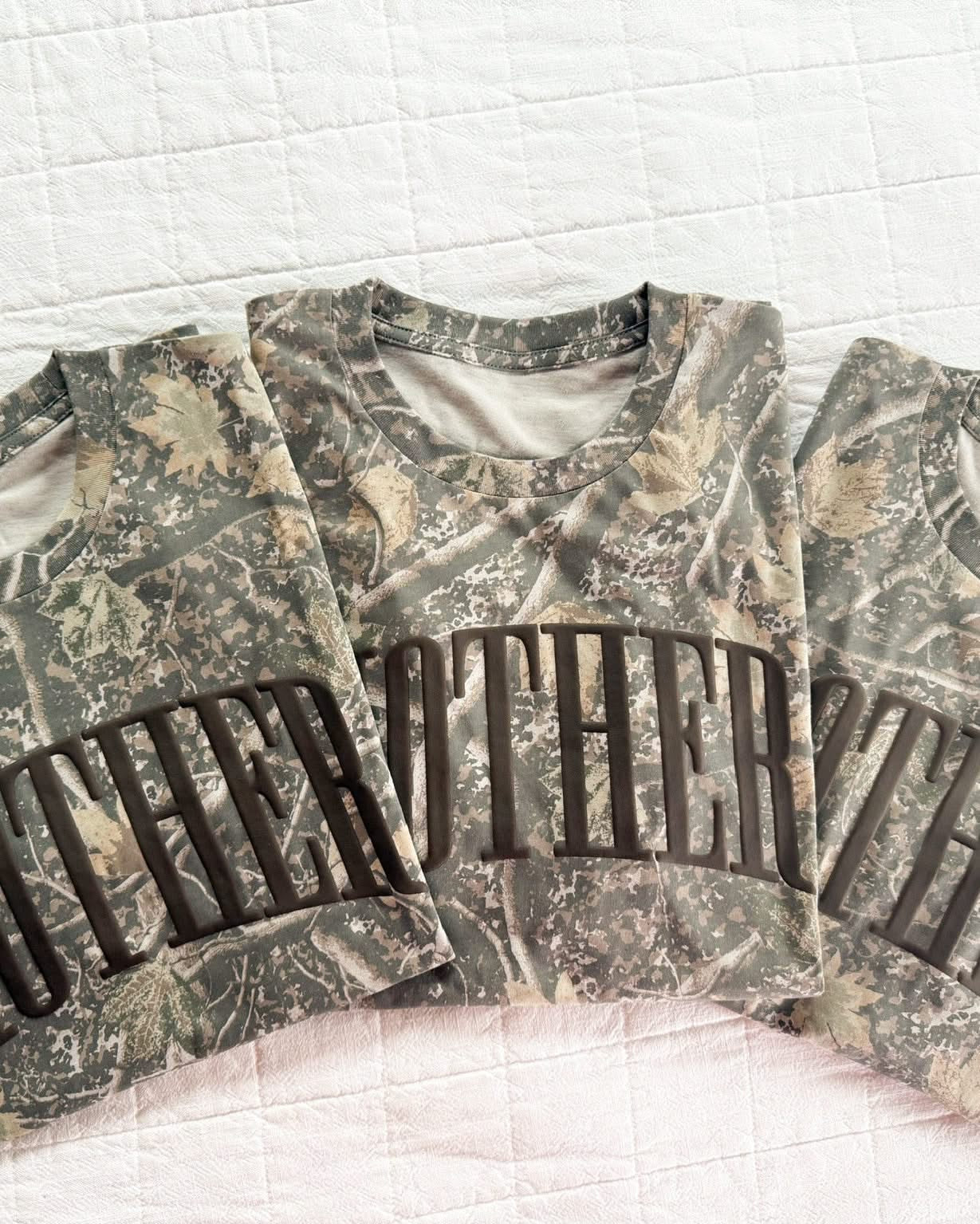 Adult camo tee with 'mother' printed on the front in puff print, seen on flat lay - Little Mama Shirt Shop